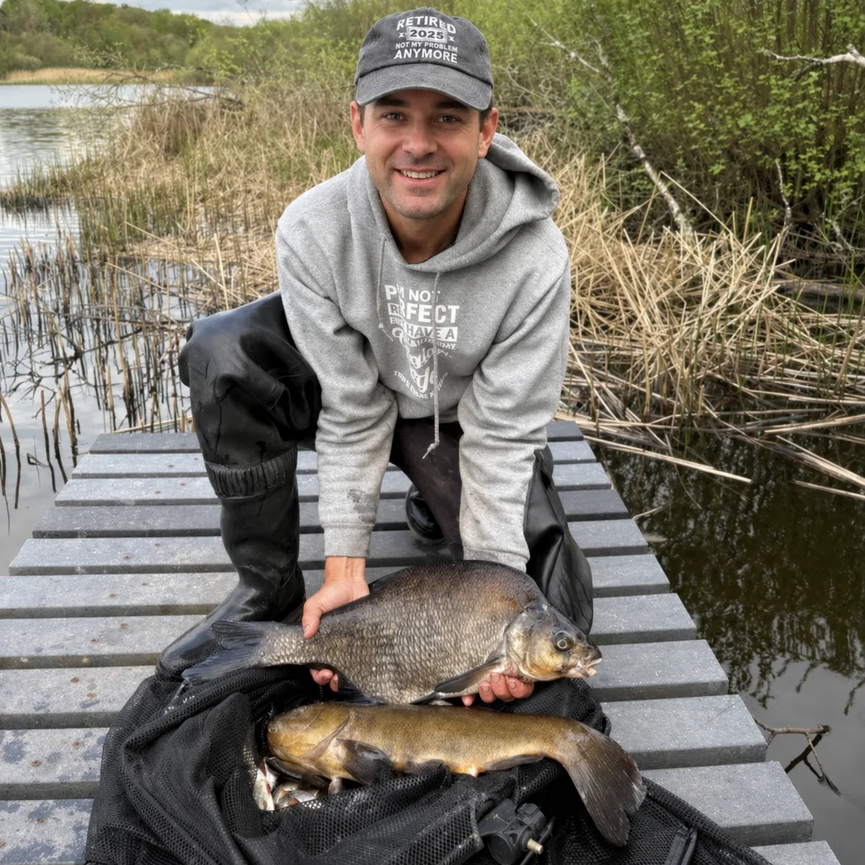 Angler with a bream and tench on a fishing platform beside an Irish fishery.